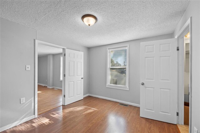 unfurnished bedroom with wood-type flooring and a textured ceiling