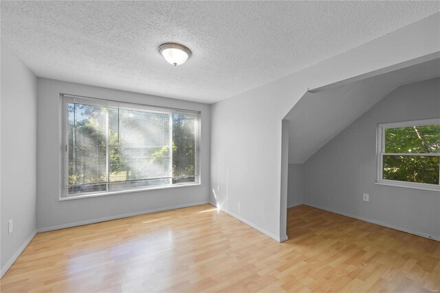 bonus room featuring a textured ceiling, light hardwood / wood-style floors, and vaulted ceiling