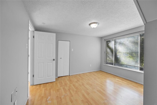 unfurnished bedroom with light wood-type flooring and a textured ceiling