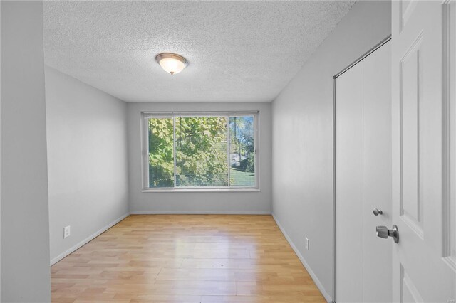 spare room with light hardwood / wood-style floors and a textured ceiling