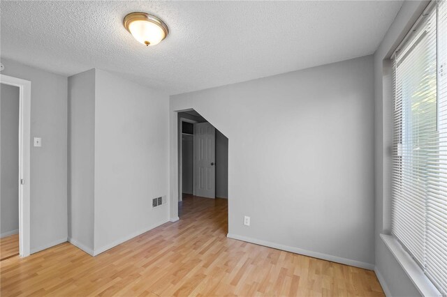 spare room featuring a textured ceiling and light wood-type flooring