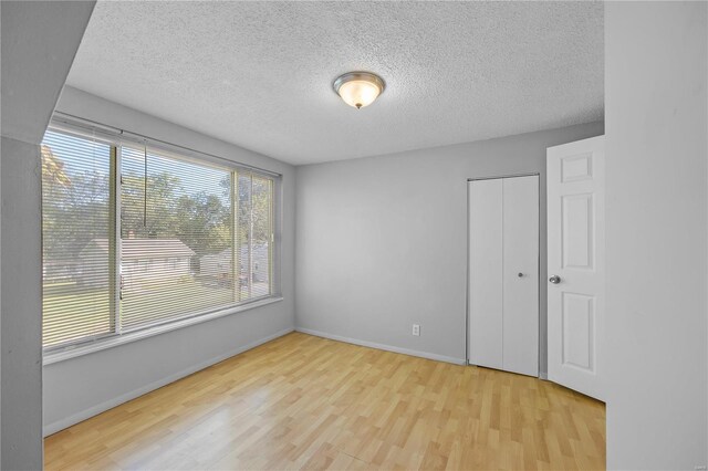 unfurnished room featuring light wood-type flooring and a textured ceiling