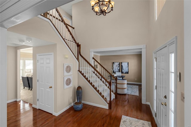 foyer entrance with dark wood-type flooring, a notable chandelier, and a towering ceiling