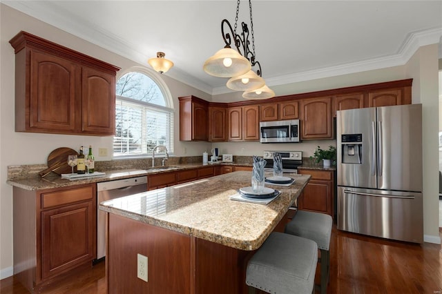 kitchen with ornamental molding, stainless steel appliances, decorative light fixtures, and a center island