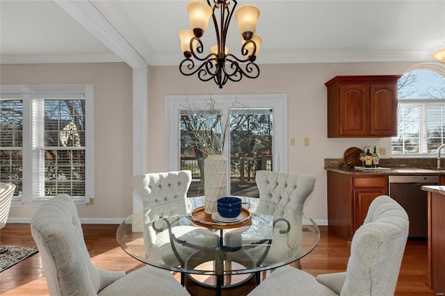 dining space featuring an inviting chandelier, crown molding, light hardwood / wood-style flooring, and a healthy amount of sunlight