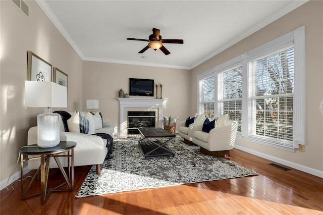 living room with crown molding, wood-type flooring, a high end fireplace, and ceiling fan