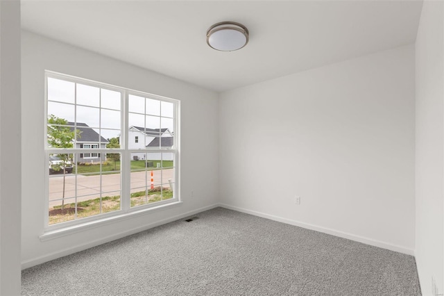 carpeted empty room featuring baseboards and visible vents