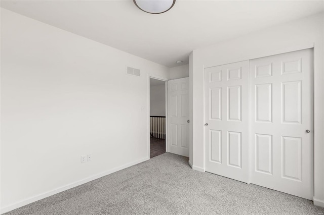 unfurnished bedroom featuring baseboards, carpet, a closet, and visible vents