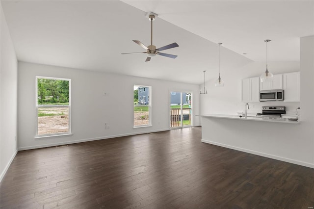 unfurnished living room with baseboards, vaulted ceiling, dark wood-type flooring, and a ceiling fan