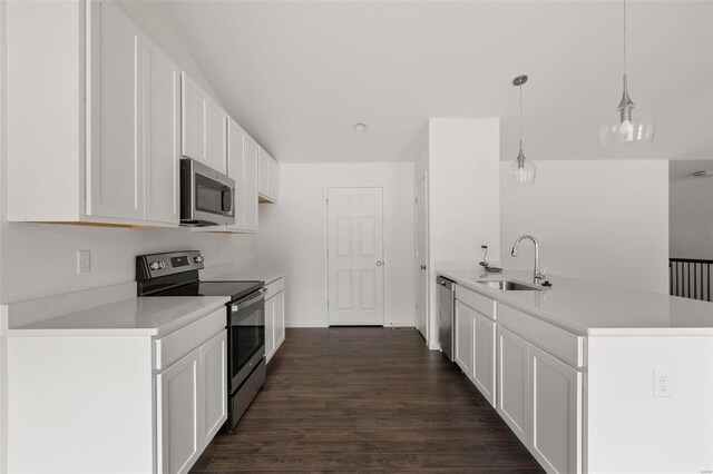 kitchen featuring dark wood-type flooring, sink, white cabinets, stainless steel appliances, and decorative light fixtures