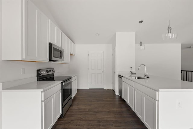 kitchen with dark wood-style flooring, light countertops, a peninsula, appliances with stainless steel finishes, and a sink