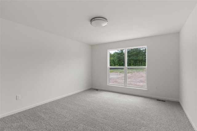 spare room featuring baseboards, visible vents, and carpet