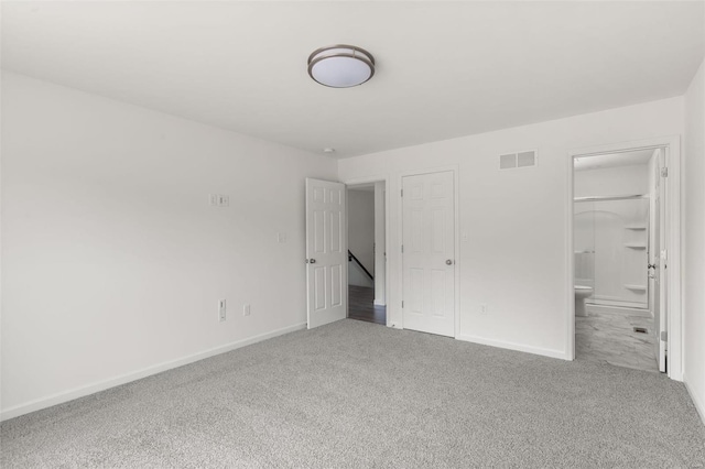 unfurnished bedroom with carpet flooring, ensuite bath, baseboards, and visible vents