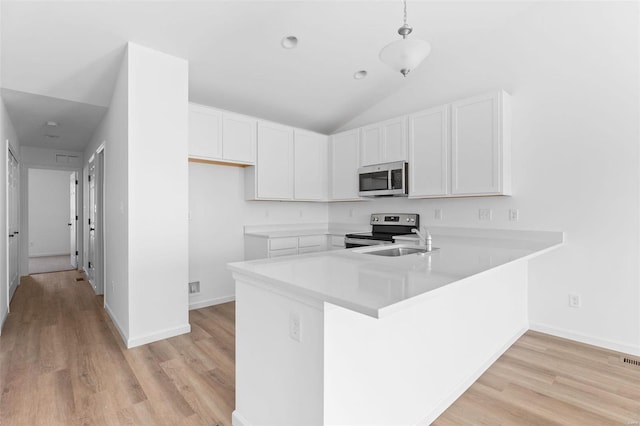 kitchen with lofted ceiling, kitchen peninsula, decorative light fixtures, white cabinetry, and appliances with stainless steel finishes