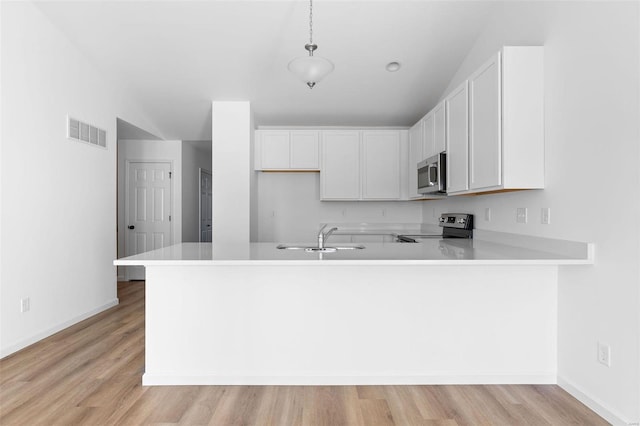 kitchen featuring light hardwood / wood-style floors, white cabinetry, kitchen peninsula, hanging light fixtures, and appliances with stainless steel finishes