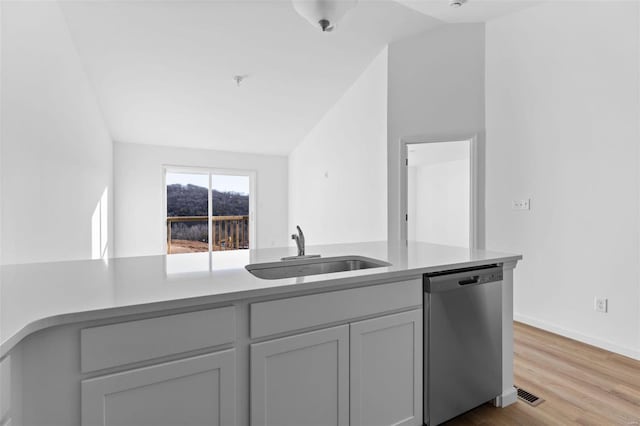 kitchen featuring light hardwood / wood-style floors, sink, vaulted ceiling, gray cabinetry, and stainless steel dishwasher