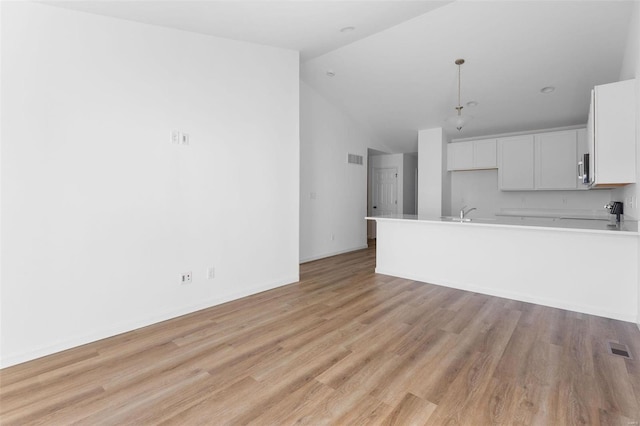 unfurnished living room featuring light hardwood / wood-style flooring, sink, and high vaulted ceiling