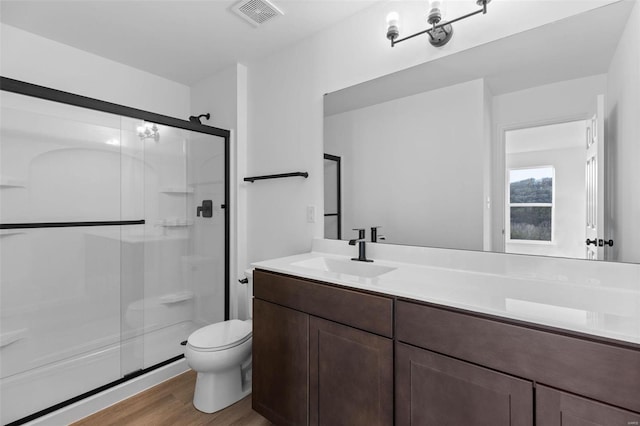 bathroom with wood-type flooring, vanity, toilet, and a shower with door