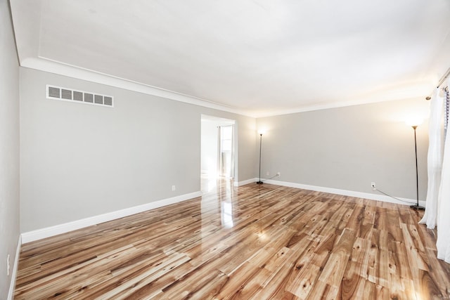 unfurnished room with crown molding and light wood-type flooring