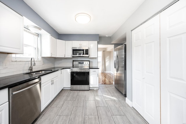 kitchen with stainless steel appliances, white cabinetry, sink, and decorative backsplash