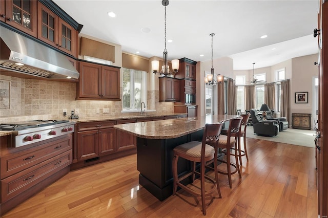 kitchen with a notable chandelier, stone counters, light hardwood / wood-style flooring, backsplash, and appliances with stainless steel finishes