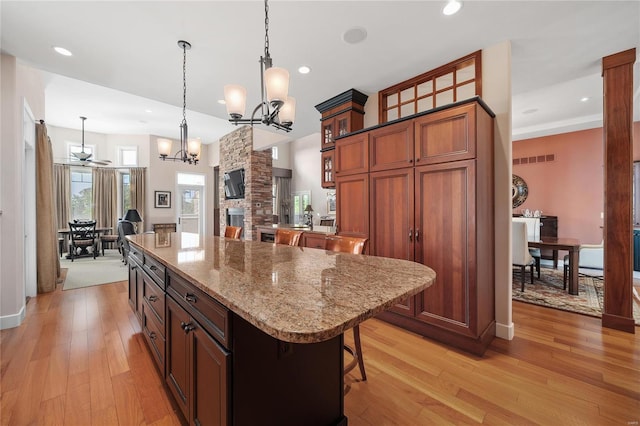 kitchen with a fireplace, hanging light fixtures, light hardwood / wood-style floors, and a kitchen island