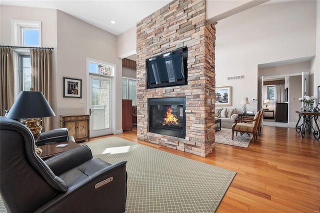 living room featuring a fireplace, a high ceiling, and a healthy amount of sunlight