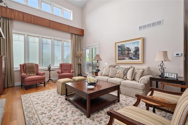 living room featuring light wood-type flooring and a high ceiling