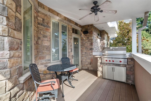 deck featuring area for grilling, ceiling fan, and exterior kitchen