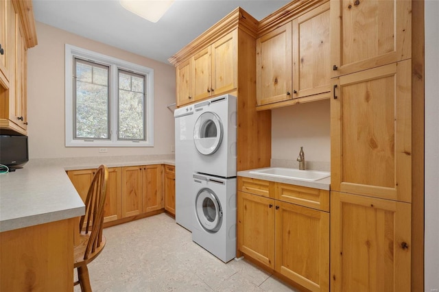 laundry area with stacked washer / drying machine, sink, and cabinets