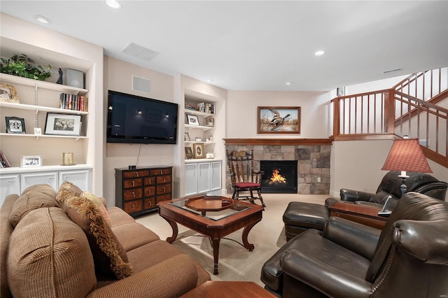 living room with light carpet, built in shelves, and a stone fireplace