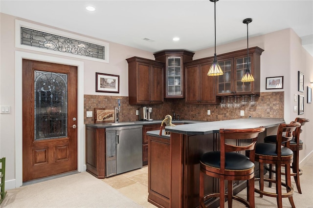 kitchen with pendant lighting, backsplash, kitchen peninsula, and dark brown cabinetry