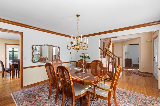 dining area with a notable chandelier, crown molding, and light hardwood / wood-style flooring