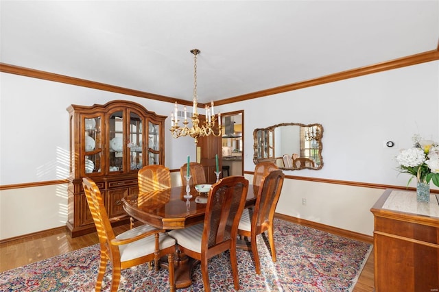 dining space with wood-type flooring, ornamental molding, and an inviting chandelier