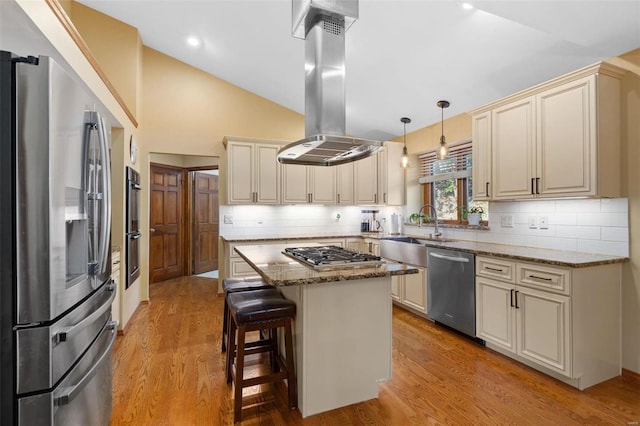 kitchen with light stone countertops, a center island, stainless steel appliances, cream cabinets, and island range hood