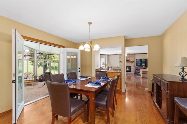 dining space with a notable chandelier, a brick fireplace, and light hardwood / wood-style flooring