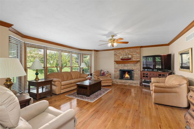 living room featuring a fireplace, light hardwood / wood-style floors, crown molding, and ceiling fan