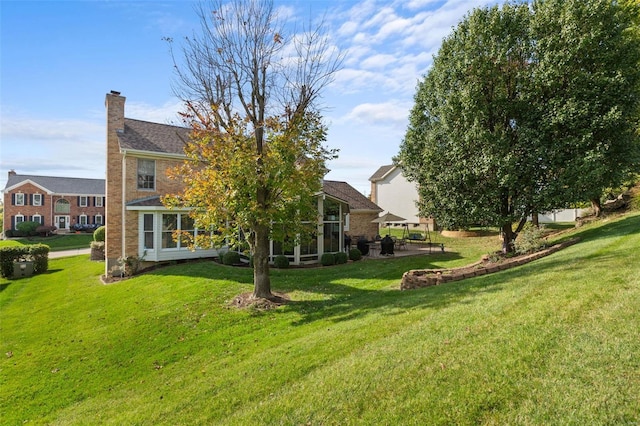 rear view of property with a sunroom, a yard, and a patio area