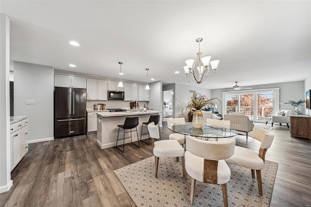 dining space with dark hardwood / wood-style floors and ceiling fan with notable chandelier