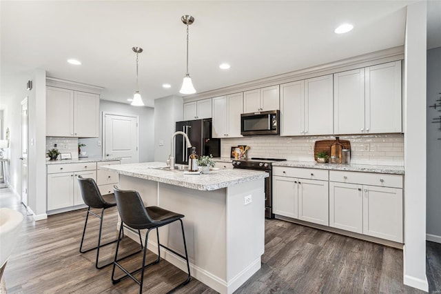 kitchen with pendant lighting, a kitchen island with sink, dark hardwood / wood-style floors, appliances with stainless steel finishes, and white cabinetry