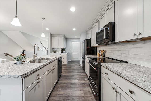 kitchen with sink, decorative light fixtures, stainless steel electric range, dark hardwood / wood-style floors, and an island with sink