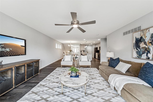 living room with ceiling fan with notable chandelier and dark hardwood / wood-style flooring