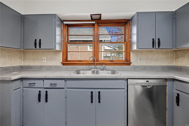 kitchen with stainless steel dishwasher, decorative backsplash, gray cabinets, and sink