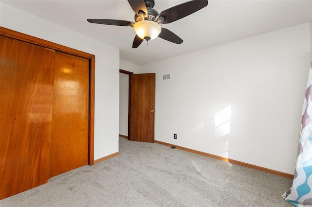 unfurnished bedroom featuring light carpet, a closet, and ceiling fan