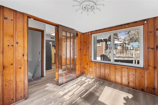 unfurnished room featuring light hardwood / wood-style floors and wood walls