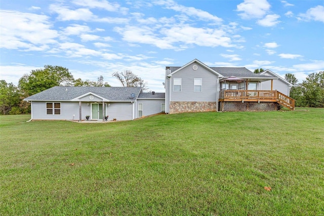 rear view of property featuring a wooden deck and a lawn