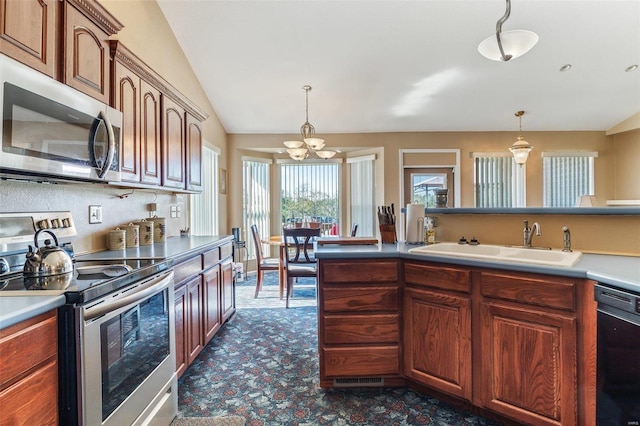 kitchen with hanging light fixtures, appliances with stainless steel finishes, sink, and vaulted ceiling