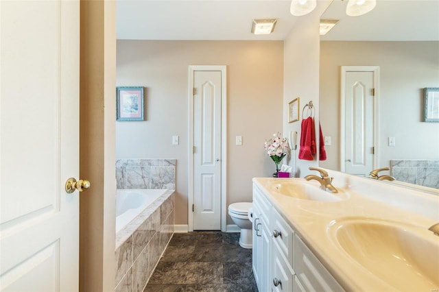 bathroom with tiled tub, vanity, and toilet