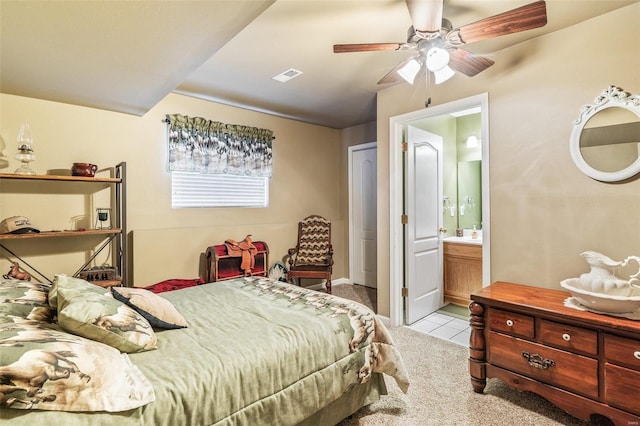 bedroom featuring ceiling fan, light carpet, and ensuite bath