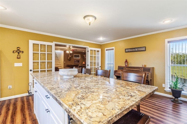 kitchen featuring dark hardwood / wood-style floors, white cabinets, a center island, and a kitchen breakfast bar